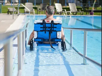 man in water wheelchair going down ramp in pool