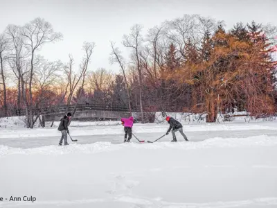 2022 2nd Place Photo - Three kids playing hockey on a frozen pond in the early evening light with a sno