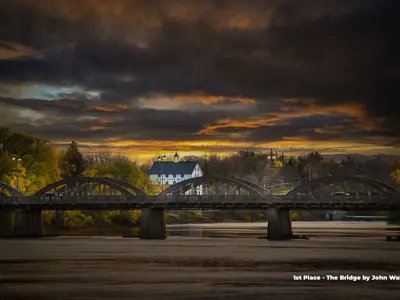 2023 1st Place Photo - Caledonia bridge under a cloudy sunset with the Grand River Mills building in the background, taken by John Wallace