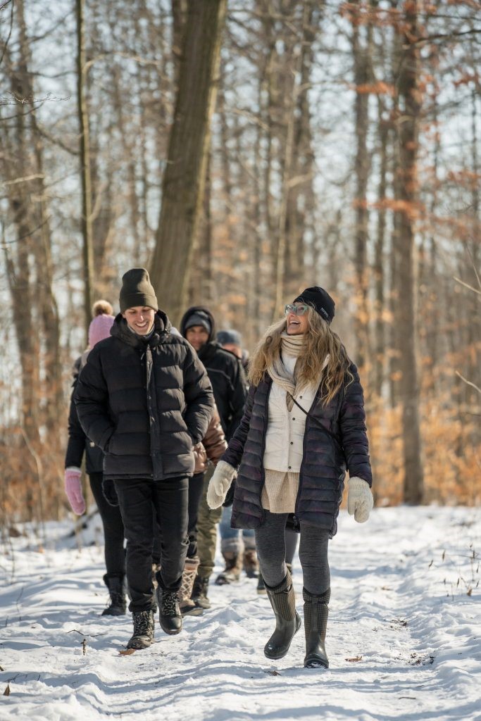 A woman leads a group of people on a walk through a wintery forest